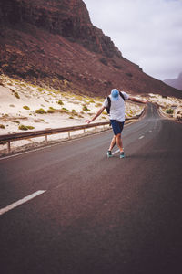 Rear view of man riding on road against mountain