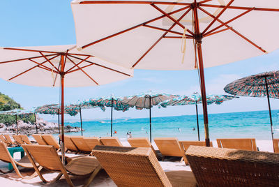 Deck chairs on beach against sky