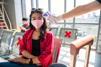 Cropped image of hand checking temperature of woman at airport