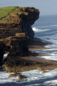 Rock formation on sea shore against sky