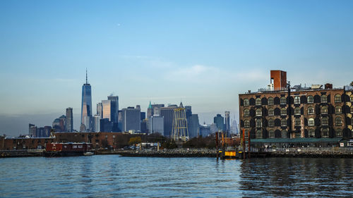 Buildings by river against clear sky