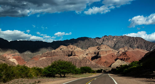 Road leading towards mountains against sky