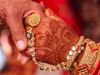 Cropped image of bridegroom holding hands with bride during wedding ceremony