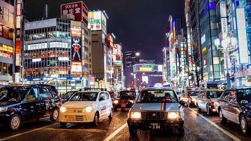 Traffic on road by buildings in city at night