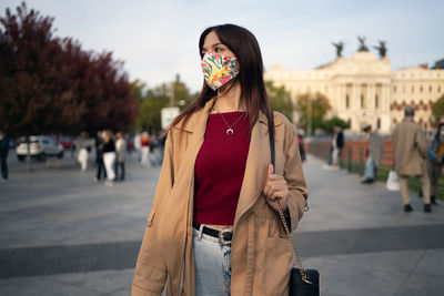 Portrait of young woman standing on street in city