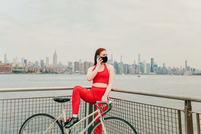 Woman riding bicycle on city skyline against sky