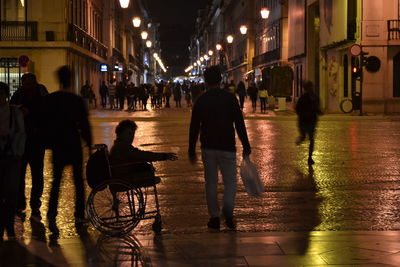 People on illuminated street in city at night