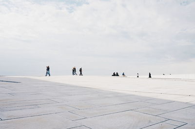 People at oslo opera house against cloudy sky