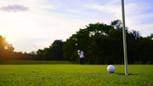 Golf ball on field against sky