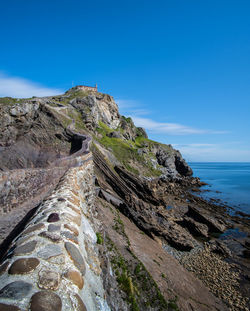 Rock formations in sea against clear blue sky