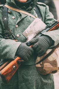 Midsection of soldier holding gun and hat