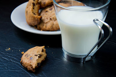 Close-up of milk cup by cookies on table