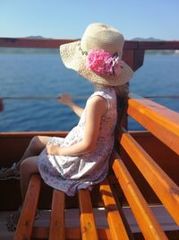 Midsection of woman sitting on pier over sea against sky