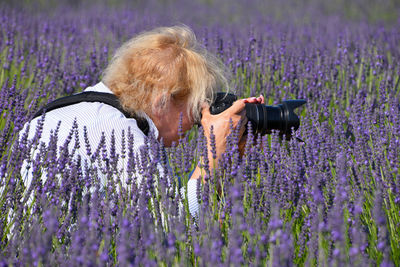 Side view of senior woman photographing lavenders on field