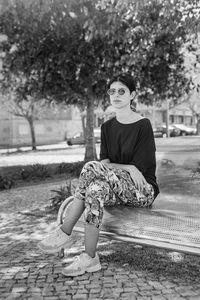 Woman looking away while sitting on tree