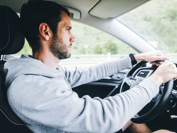 Young man driving car on highway.