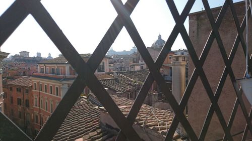 Buildings against sky seen through chainlink fence