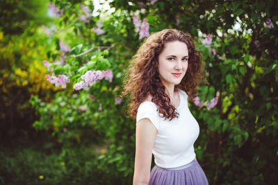 Cheerful young woman in a white t-shirt under the blooming trees. spring park with lilac