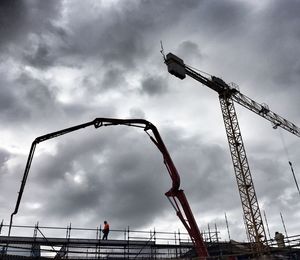 Low angle view of crane against cloudy sky
