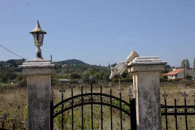 Statue by gate against clear sky