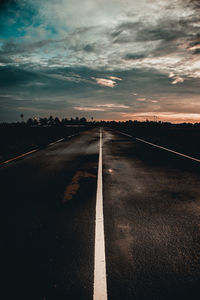 Surface level of road against sky at sunset