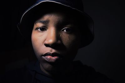 Portrait of teenage boy wearing hat in darkroom