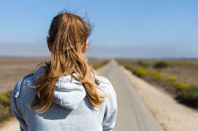 Rear view of woman standing on road against clear sky