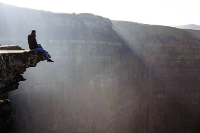 Man on cliff against sky