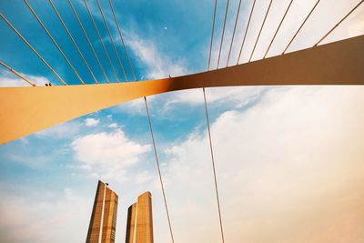 Low angle view of suspension bridge against cloudy sky