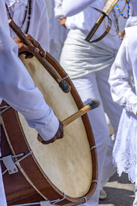 Midsection of man playing drum by crowd during festival 