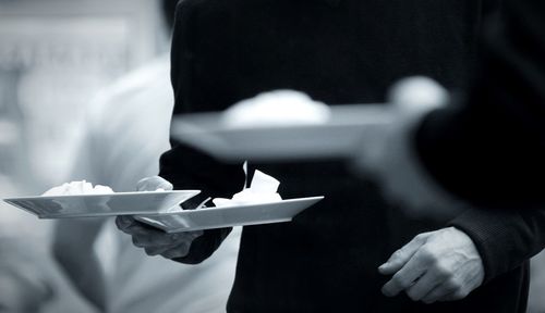 Midsection of waiters holding food in plate at restaurant