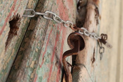 Close-up of rusty chain hanging on metal door