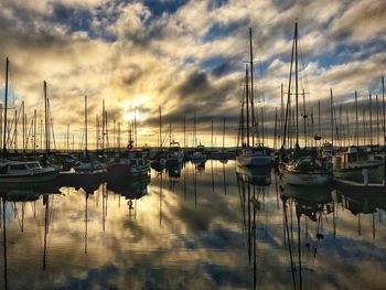 Sailboats moored in lake against sky during sunset