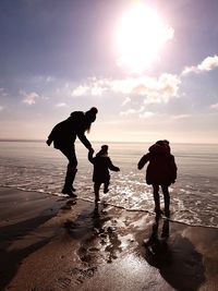 Silhouette people on beach against sky during sunset