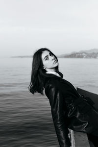 Portrait of young woman standing in sea against sky