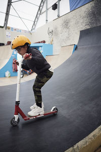 Boy learning how to ride push scooter in indoor skatepark