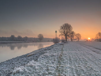 Scenic view of frozen landscape against sky at sunset