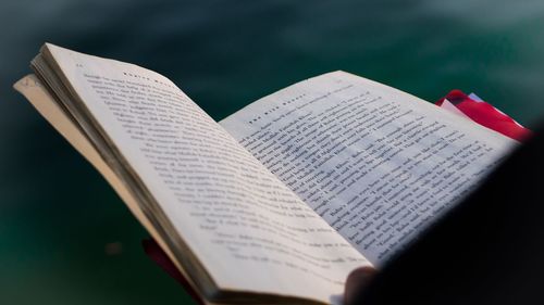 Close-up of open book against lake