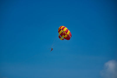 Low angle view of person paragliding against blue sky