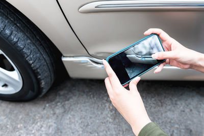 Midsection of woman holding smart phone in car