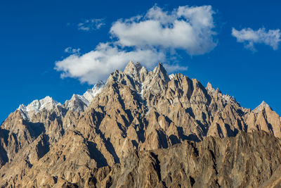 Low angle view of rocky mountains against blue sky