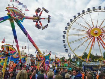 Low angle view of ferris wheel against cloudy sky