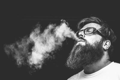 Close-up of man smoking against black background