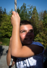 Happy boy hanging from rope at park