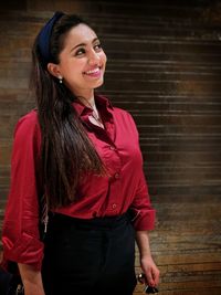 Young woman smiling while standing against brick wall