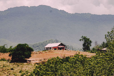 House on field by mountains against sky