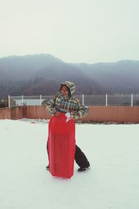 Woman with snowboard standing outdoors during winter