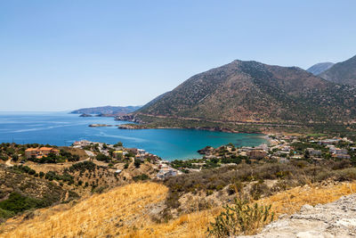 Scenic view of sea and mountains against clear blue sky