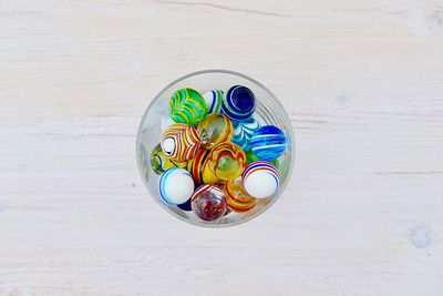 Close-up of multi colored marble balls in bowl on table