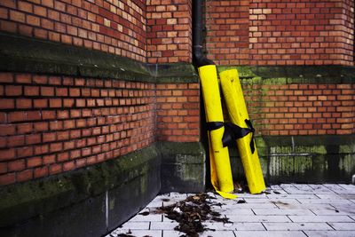 Yellow rolled tarpaulins against brick wall